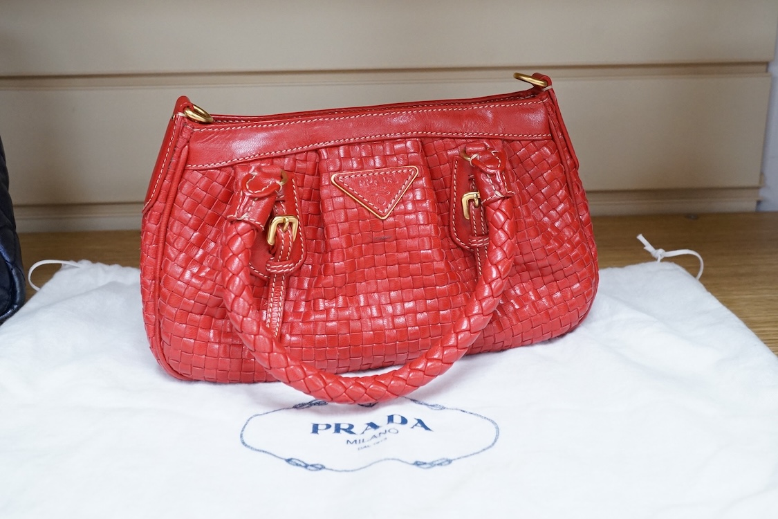 A Prada red braided leather handbag with shoulder strap, authenticity card and dust cover, 25cm wide, Provenance: Purchased by the vendor in Selfridges